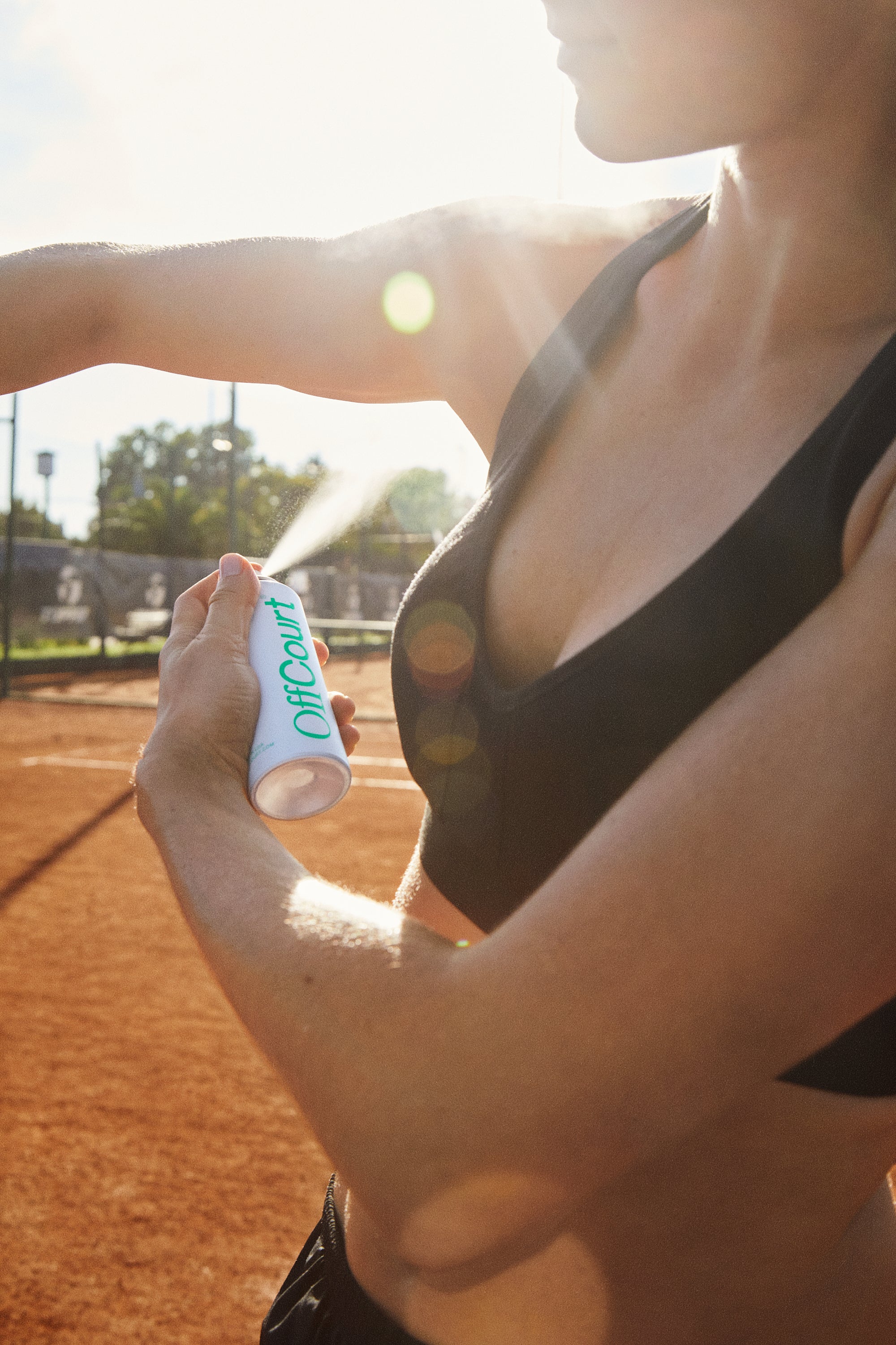 A woman spraying a body spray under her arm