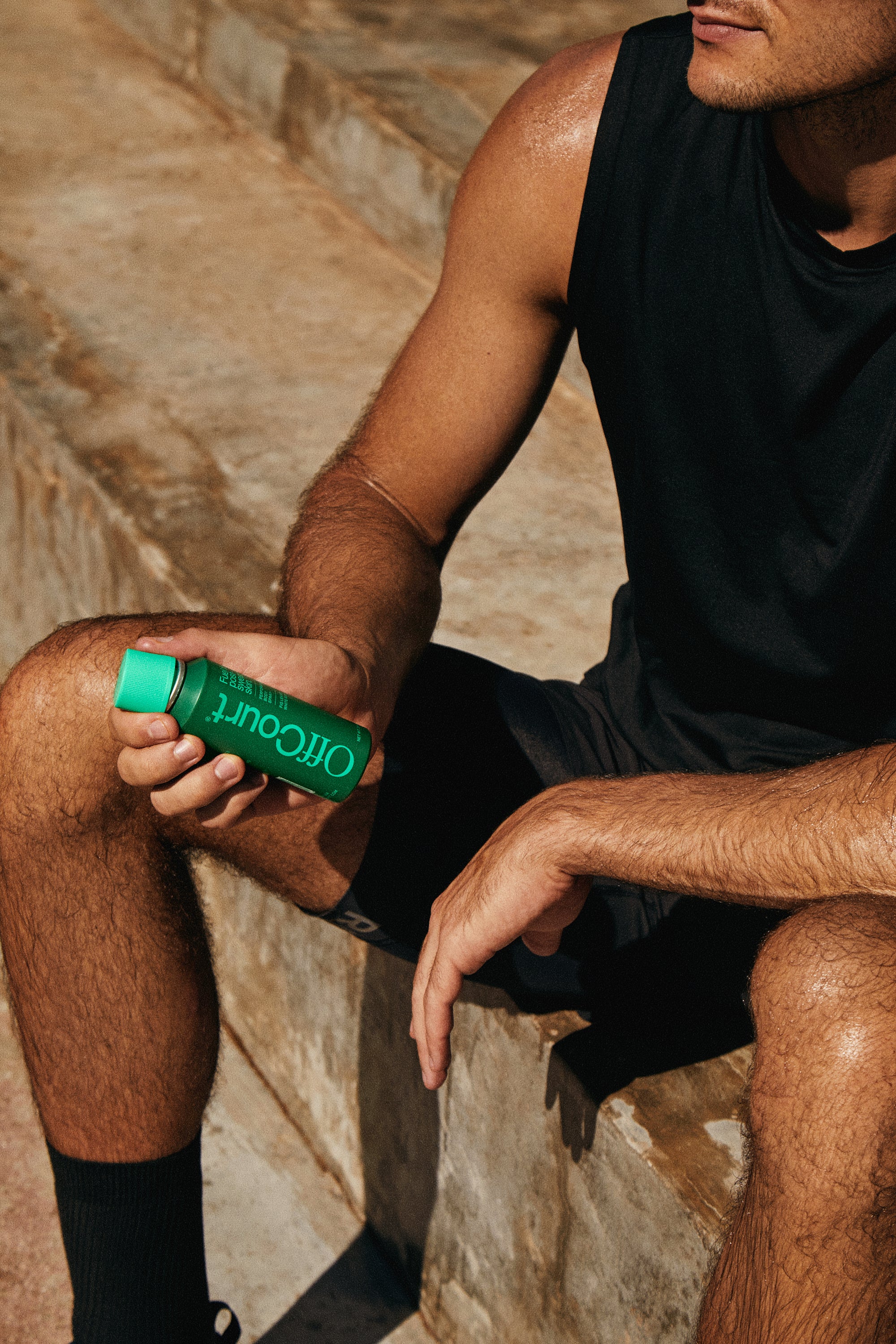 An athletic man holding a body spray in hand