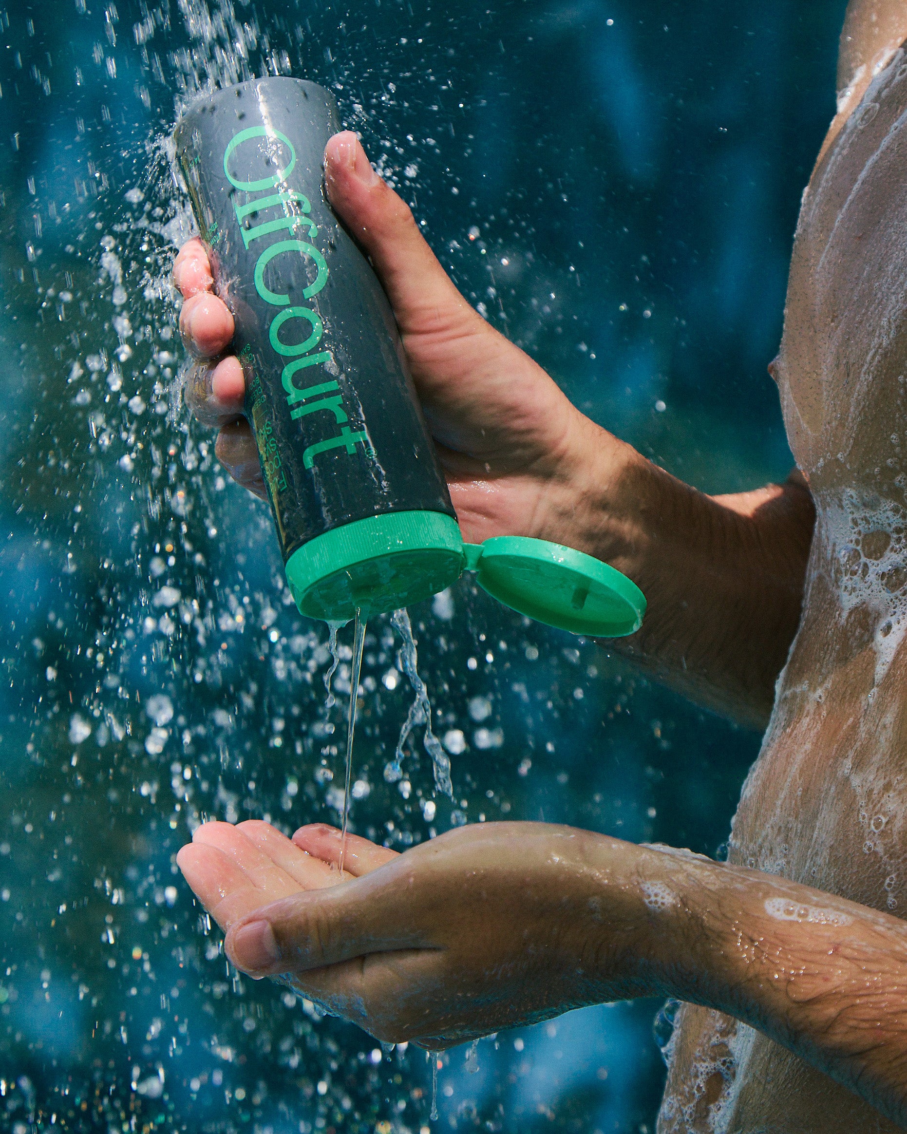 A man is holding a bottle of Deep Cleaning Body Wash in Coconut Water + sandalwood scent