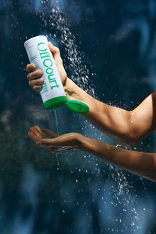 Woman squeezing a bottle of Deep Cleansing Body Wash in Fresh Citron + Driftwood fragrance