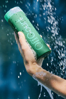 A woman squeezing a bottle of fig leaves + white musk body wash