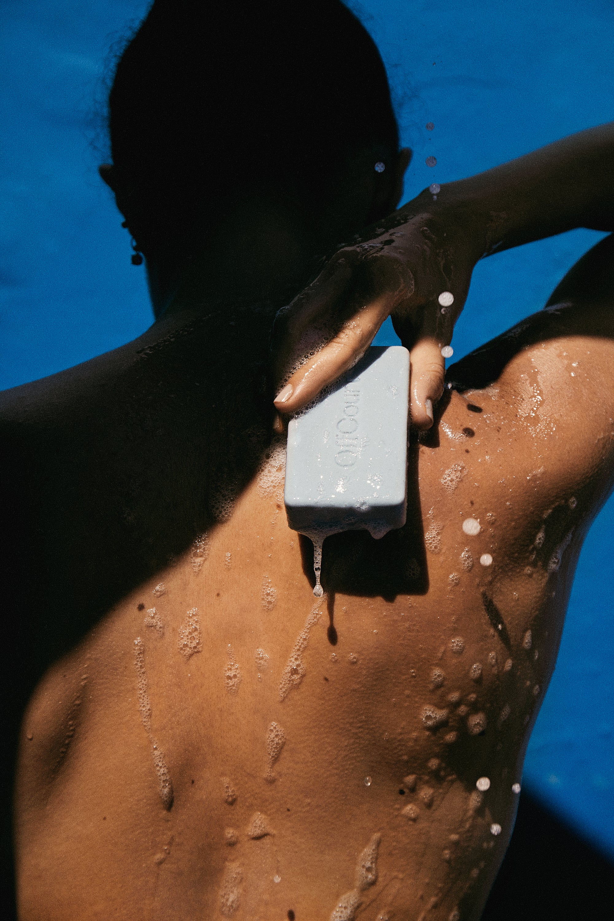 Woman holding a bar of soap on her back