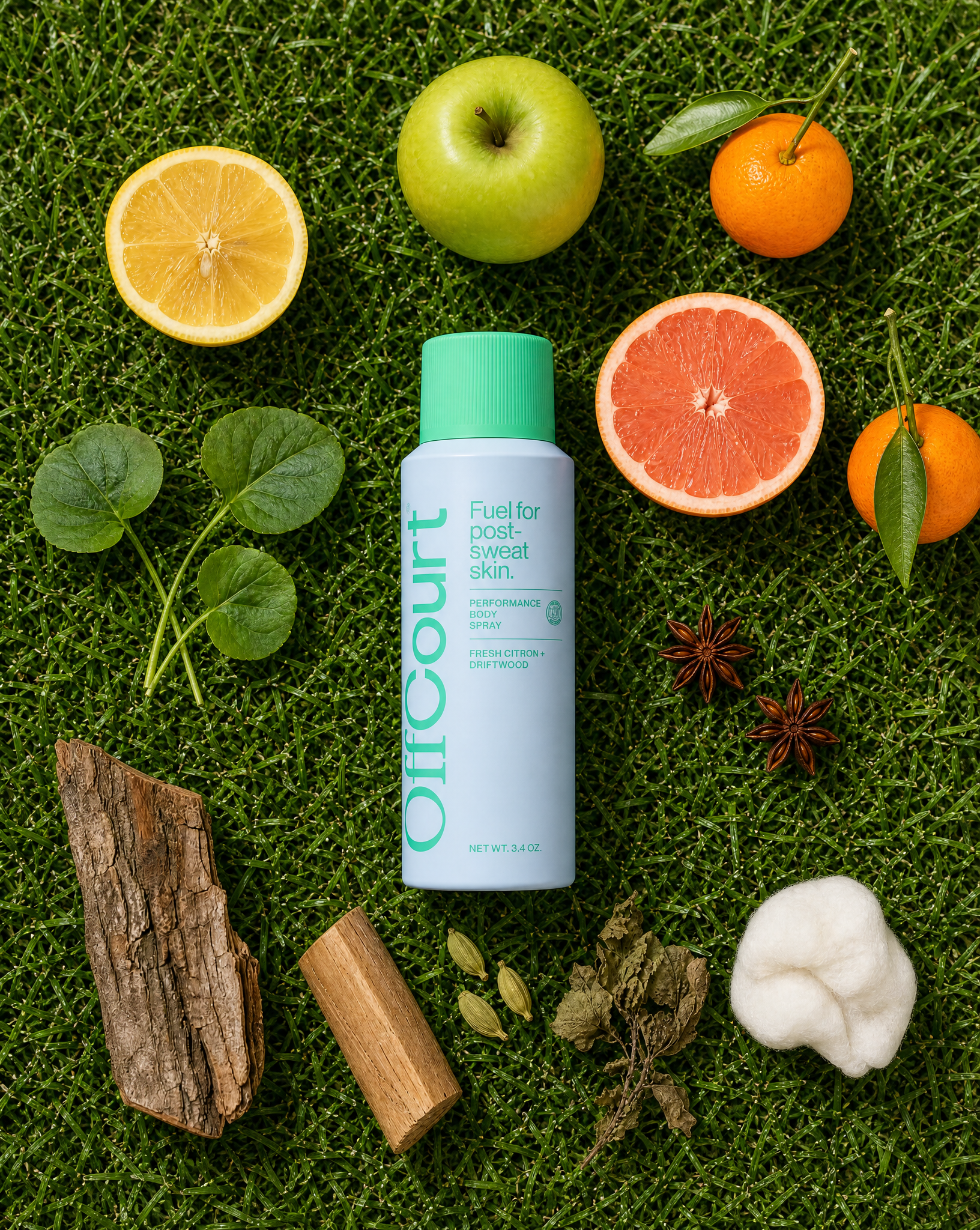 Fresh Citron + Driftwood body spray surrounded by lemon, apple, mandarin, grapefruit, anise, leaves, wood, and cotton on grass