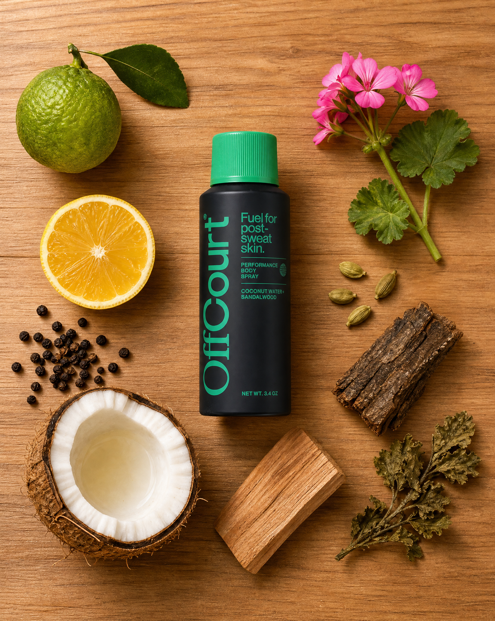 Coconut Water + Sandalwood body spray on wood, surrounded by lime, lemon, pink geranium, black peppercorns, coconut, cardamom, and bark